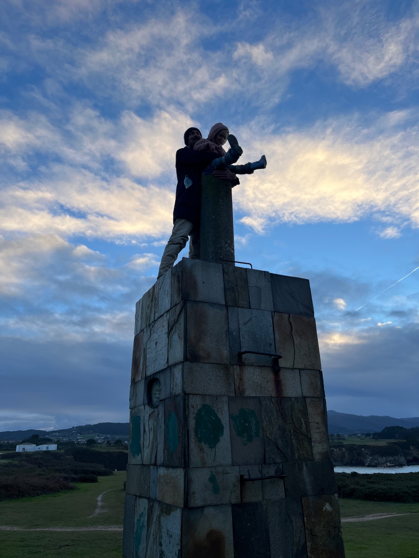 Silhouette atop a stone monument at dusk